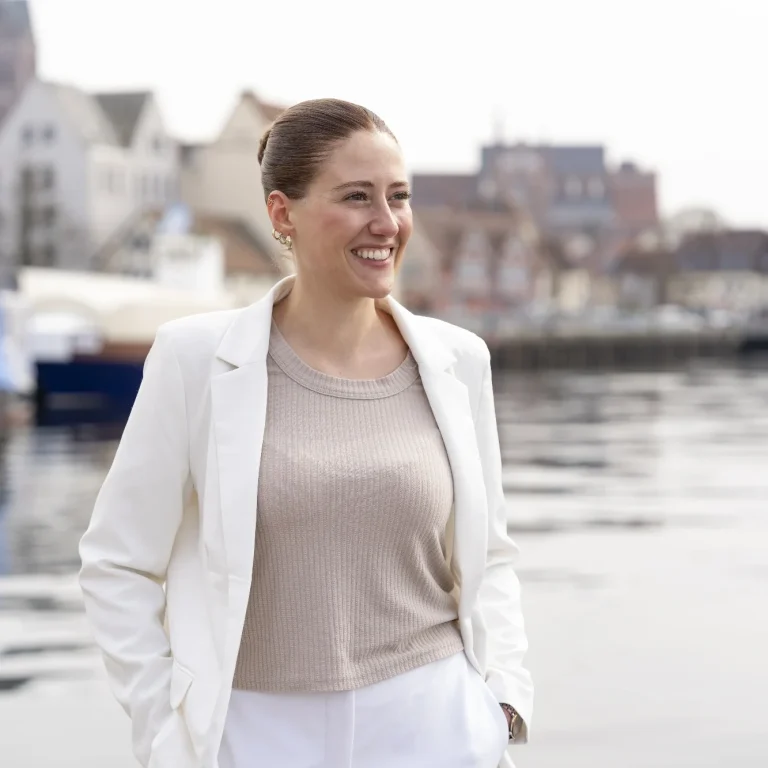 Thesis Coaching durch ThesisKompass Coachin Leonie Annika Schlecht denkt an ihre Vision und blickt dabei in die Ferne, im Hintergrund ist das Wasser der Wismarer Bucht zu sehen
