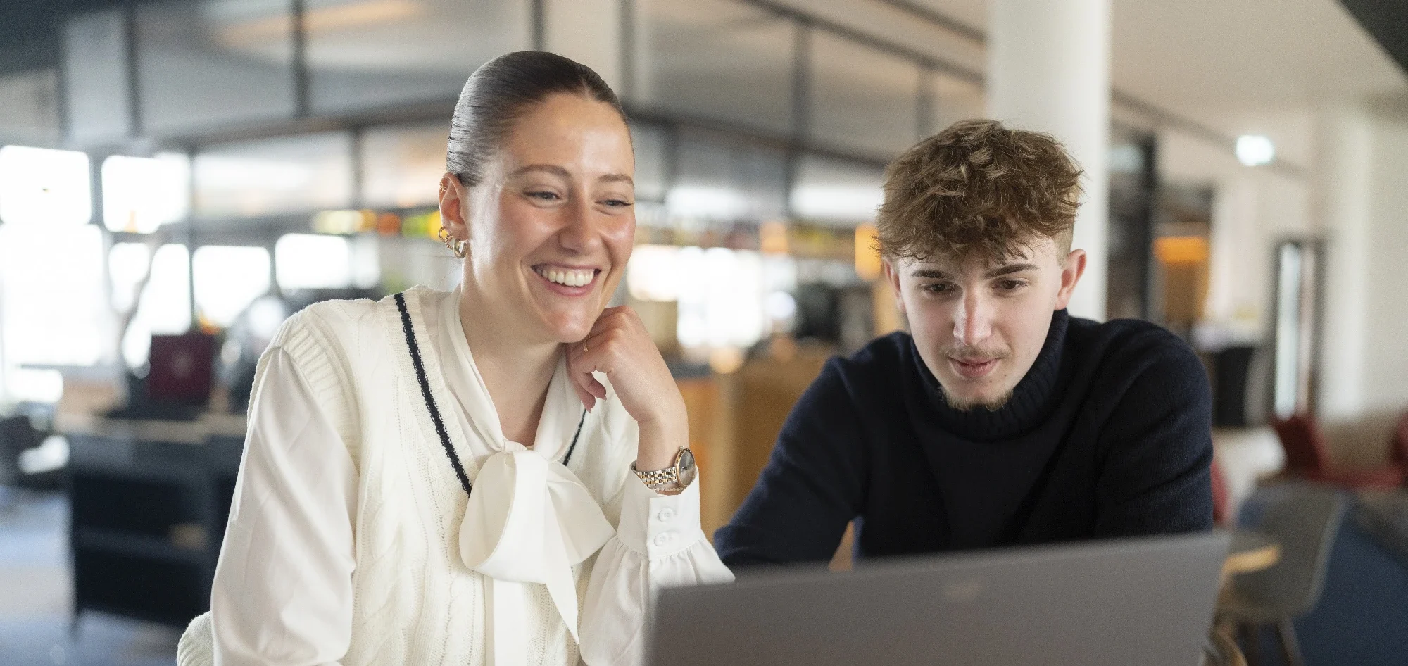 Coaching Bachelorarbeit schreiben ThesisKompass Coachin sitzt mit Teilnehmer vor dem Laptop, beide lächeln und besprechen etwas